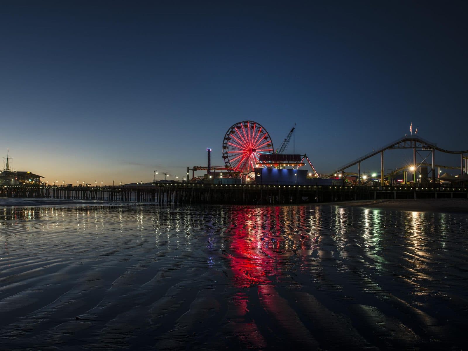 Mobile car detailing in Santa Monica — Santa Monica Pier Santa Monica Pier and Pacific Park Ferris wheel lit up at sunset, reflected on the beach in Santa Monica, California